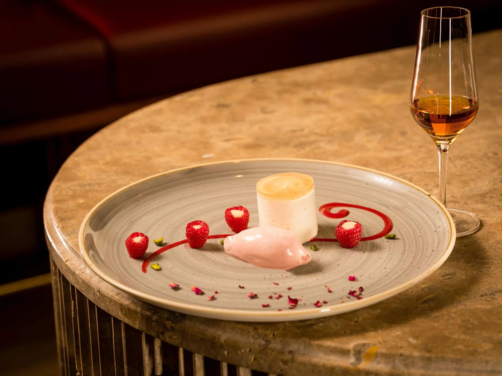 Nachspeise auf Teller mit Himbeeren angerichtet, daneben steht ein Digestif
